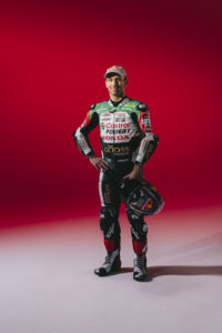 Johann Zarco debout combinaison MotoGP Dafy Moto casque Shark main gauche fond rouge Nicolas Jacquemin photographe